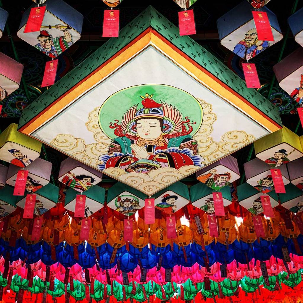 A canopy of vibrant paper lanterns in red, orange, yellow, green, blue, and pink hanging from the ceiling. 