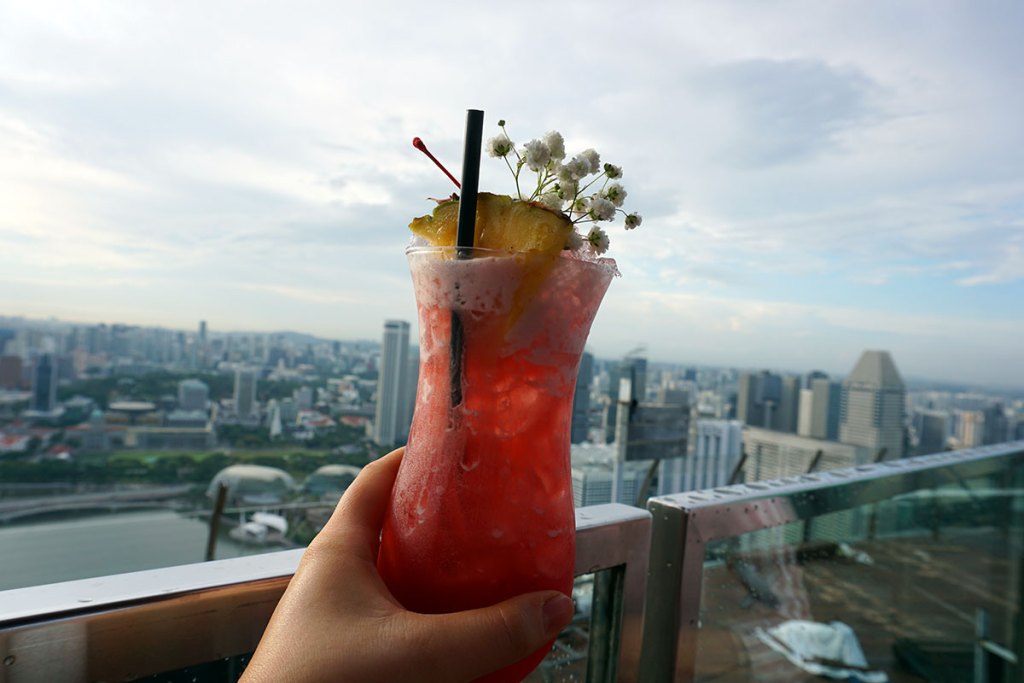 Singapore Sling cocktail in front of city skyline