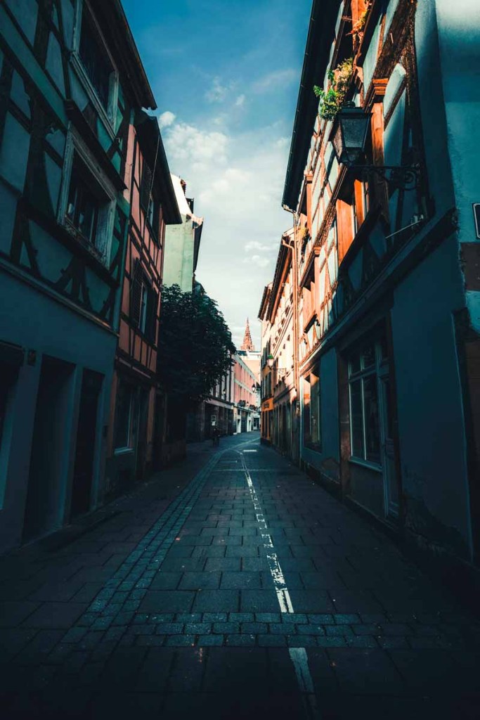 Narrow street in Europe with colorful houses providing shade