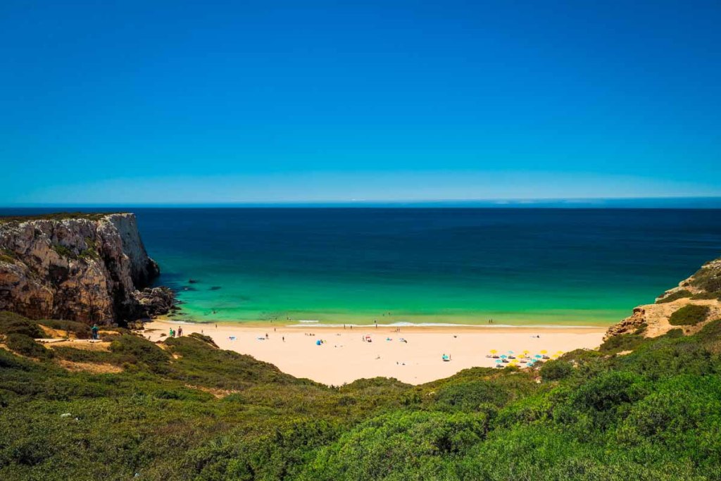This image shows a stunning beach with turquoise waters, golden sand, and dramatic cliffs. The vibrant colors and serene atmosphere make it an idyllic coastal getaway.