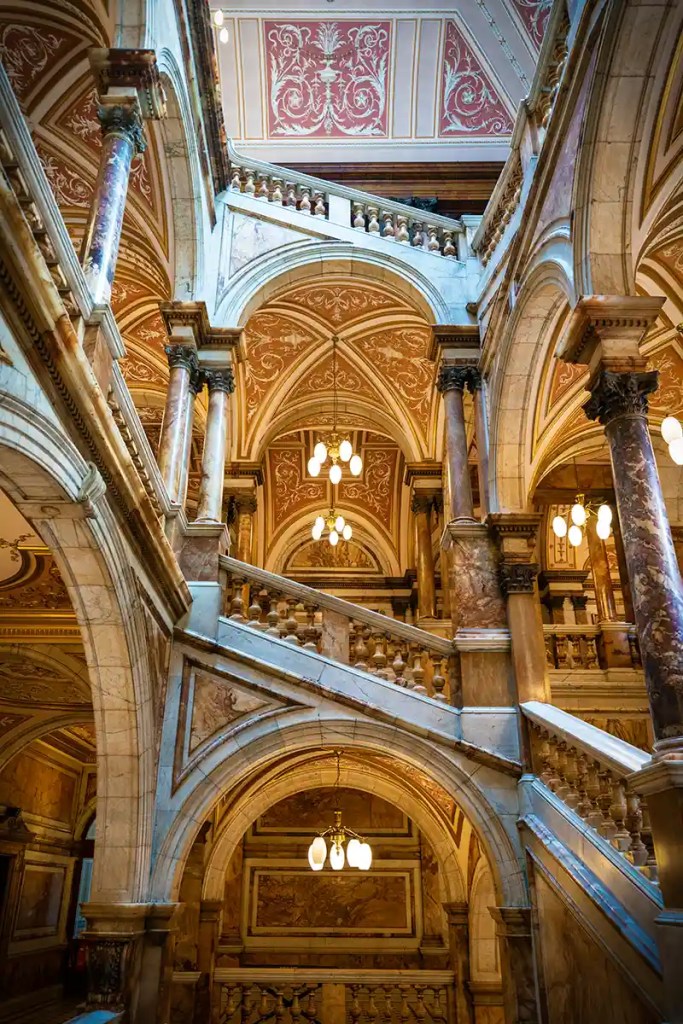 Ornate marble staircase inside Glasgow City Chambers featuring arches, columns, and decorative painted ceilings.