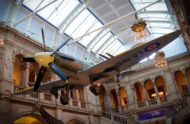 Vintage aircraft suspended inside Kelvingrove Art Gallery and Museum beneath a glass ceiling and ornate historic architecture.